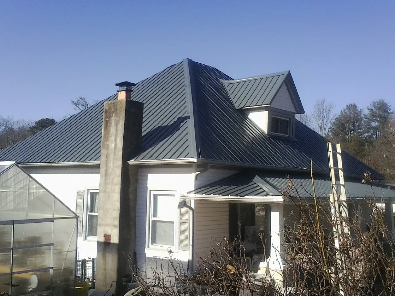 Dark blue standing seam metal roof on a white farmhouse with dormer — Slate & Tile Roof Repair by Roofing Brothers in Elco