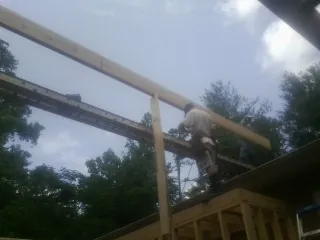 Carpenter setting a ridge beam over a new addition frame — Ice Dam Removal by Roofing Brothers in Elco