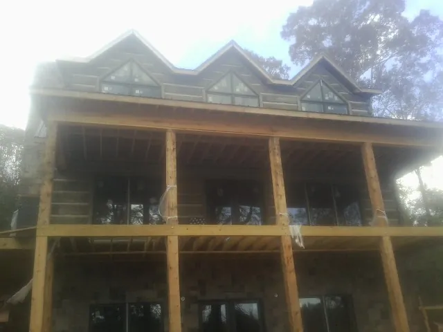 Dormers and porch framing on a large log home under construction — Roof Coating work by our crew in Elco