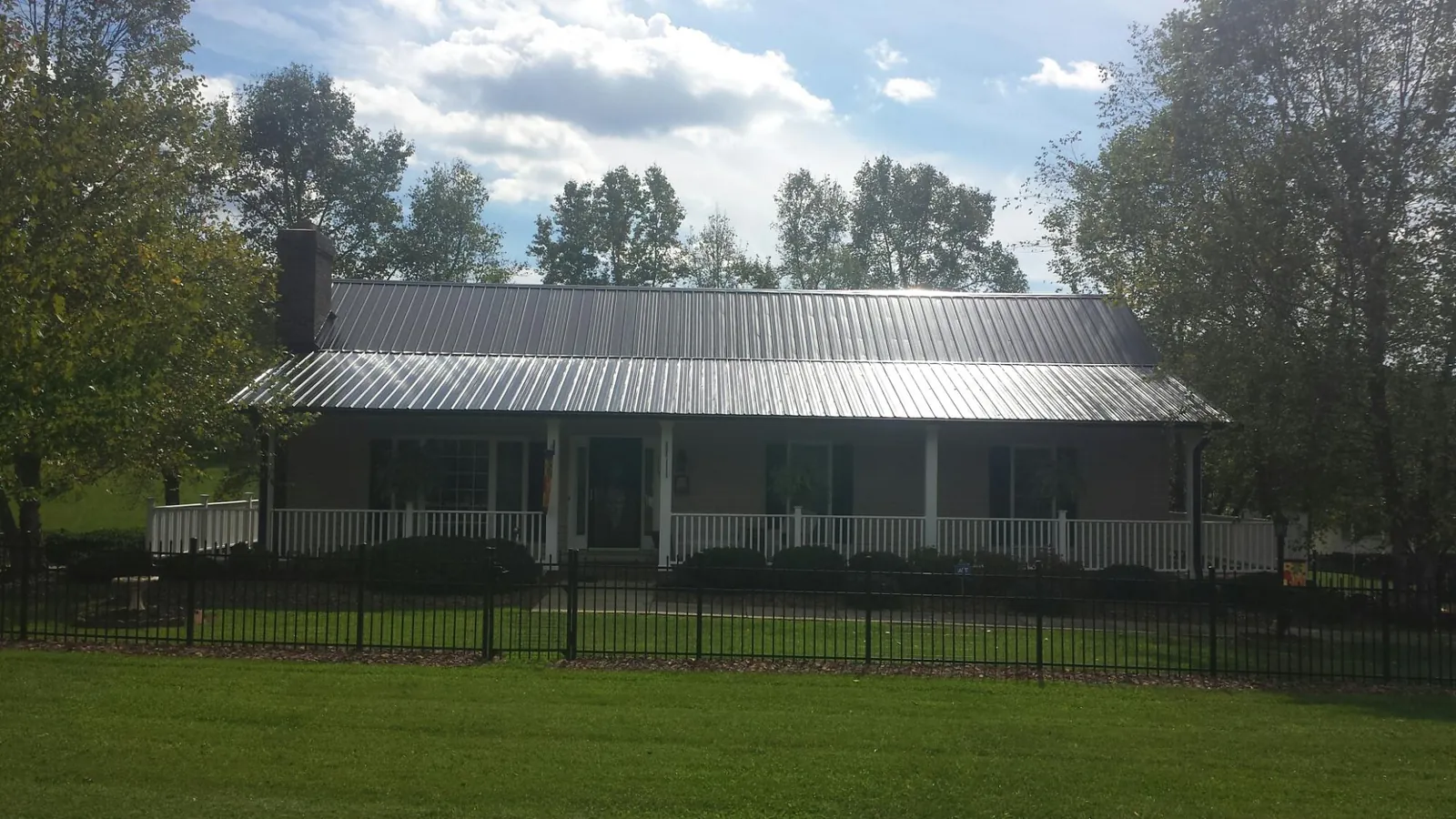 Gray metal roof on a brick ranch with a full width front porch — Gutter Guard Installation work by our crew in Elco