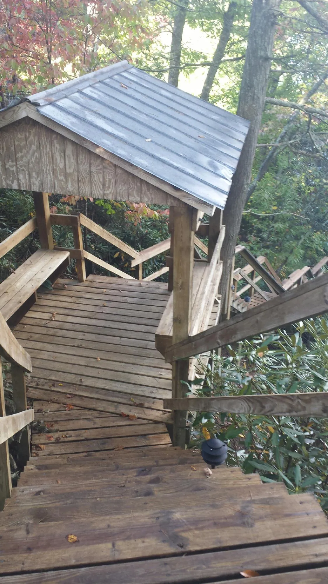 Metal roofed shelter over wooden steps on a wooded walkway — Skylight Repair & Installation work by our crew in Elco