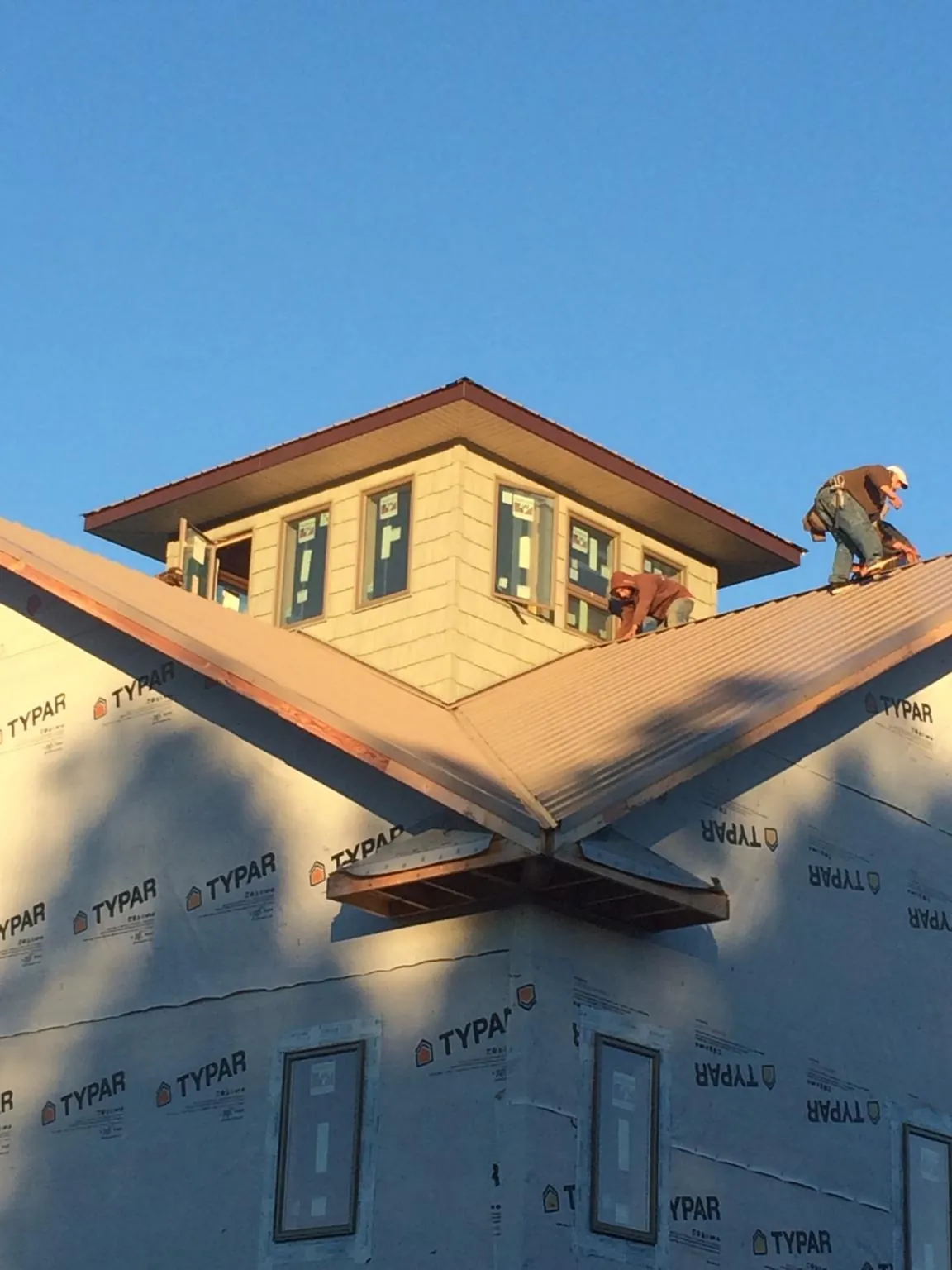 Roofers working around a rooftop cupola on a new metal roof at sunset — Roof Waterproofing in Elco by Roofing Brothers
